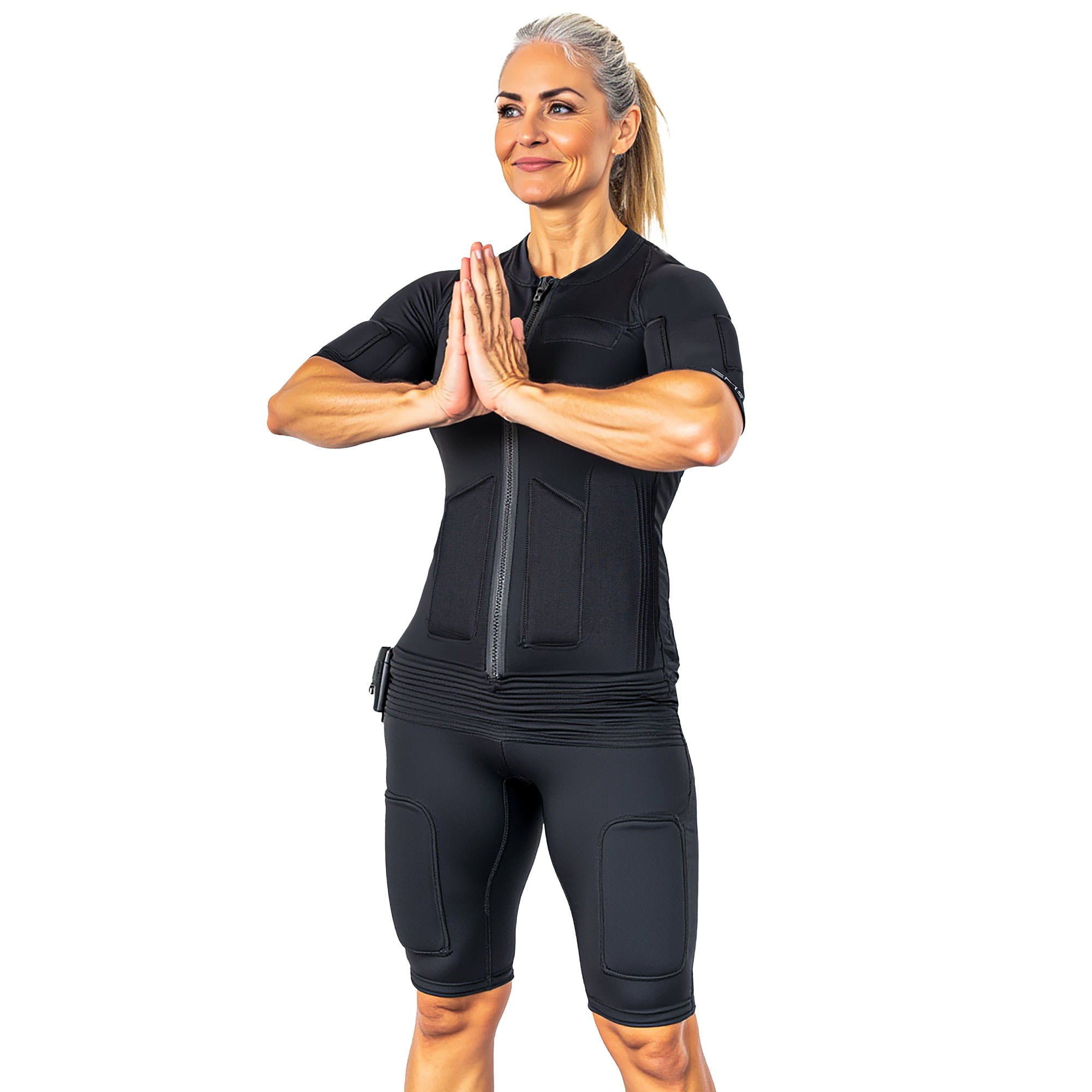Fit woman in black EMS suit doing namaste pose, looking left with blonde ponytail